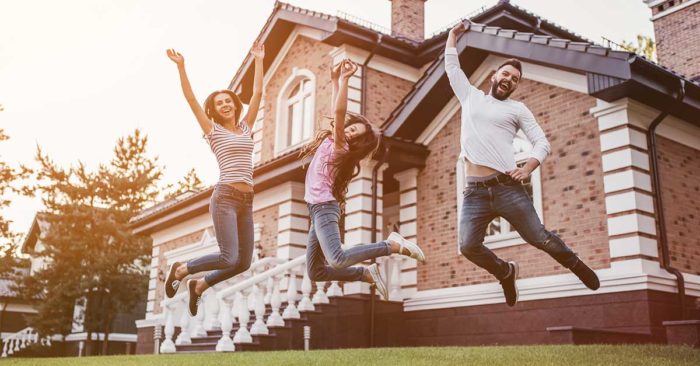 image of a family jumping together in front of a house