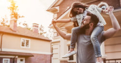 young father holding daughter on shoulders in front of home | Honor Credit Union