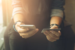person holding a credit or debit card in one hand and a mobile phone in the other hand | Honor Credit Union