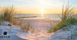 A picture of a sandy beach at sunset with Honor Credit Union's logo in the bottom left corner. | Honor Credit Union