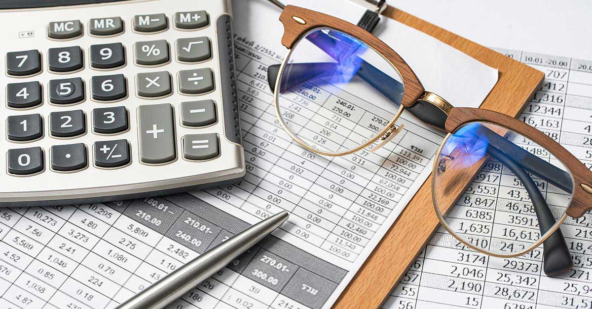learn how the prime rate change might affect you; calculator, glasses, pen, and paperwork resting on a table