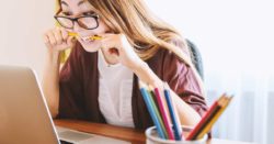 student loan debt is frustrating for many college graduates; photo of woman biting a pencil looking at a computer screen | Honor Credit Union