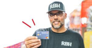 Man in RBH uniform holding a blue Honor Mastercard toward the camera in a store setting. | Honor Credit Union