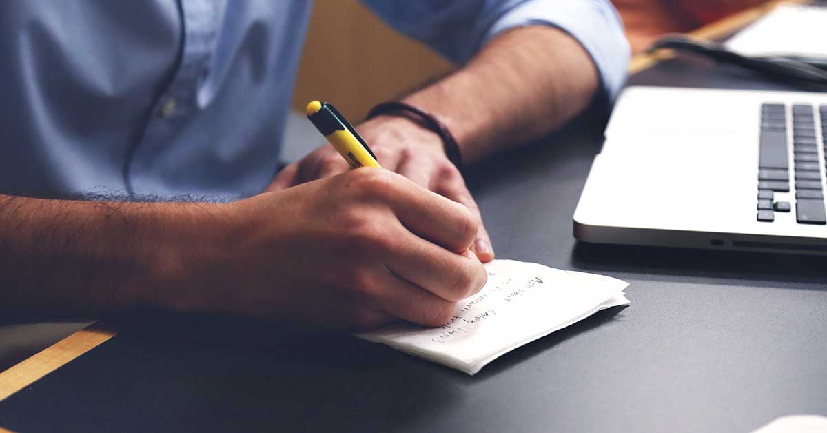 honor credit union has tips to help your business get started; photo of man holding a pen writing notes on paper