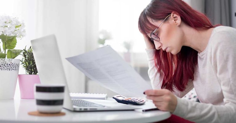 transfer a credit card balance to honor credit union; woman looking at papers at a table with a calculator