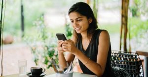 image of a woman with dark hair sitting on a covered patio looking at her phone | Honor Credit Union
