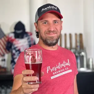 Jake Lohse holding up a beer at Presidential Brewing | Honor Credit Union
