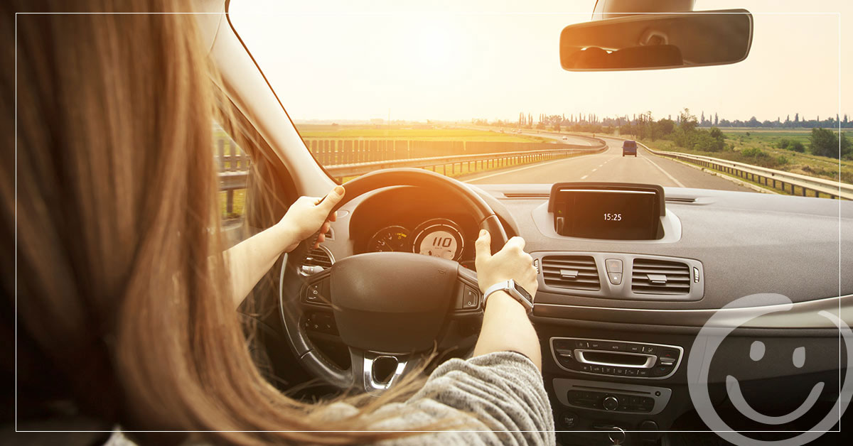photo of a woman driving a car on an empty road as the sun sets