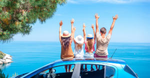 a family sitting with their backs to the camera, on the top of a car with their hands in the air | Honor Credit Union
