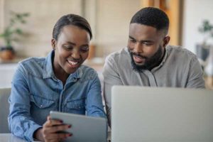 man and woman sitting next to each other smiling and looking at a tablet device | Honor Credit Union