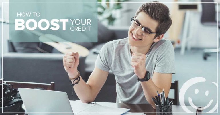 image of a man sitting at a desk looking at a laptop while smiling and clenching his fists