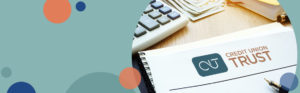 image with a teal background and a photo of a notebook with a credit union trust logo on it | Honor Credit Union