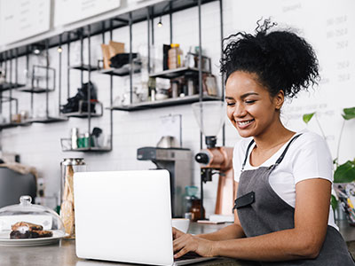 photo of a woman standing at a work table looking at a laptop