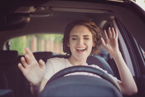photo of a woman smiling and having fun in the driver's seat of a vehicle | Honor Credit Union