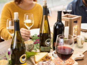 photo of people sitting at a table with cheese and Round Barn wine bottles | Honor Credit Union