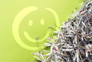image featuring a stack of shredded paper sitting next to a green wall that has a white smiley face on it | Honor Credit Union