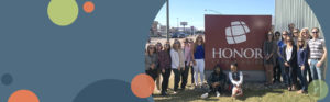 image featuring a blue background with green and orange circles on the left with a photo of honor team members standing outside of a member center on the right | Honor Credit Union