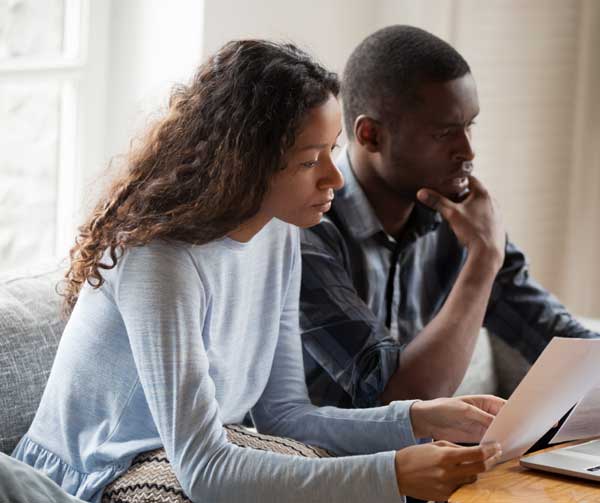 photo of a couple looking over paperwork while sitting on a couch together