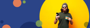man wearing sunglasses holding a phone against a yellow background | Honor Credit Union