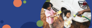 two kids smiling while being sprayed with water while washing a car | Honor Credit Union