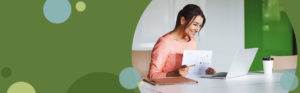 woman sorting through business documents while looking at a laptop computer screen | Honor Credit Union
