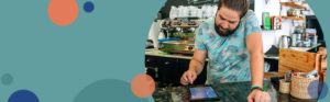 small business owner looking at a tablet device behind the counter of a coffee shop | Honor Credit Union