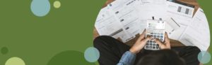 person using a calculator with papers scatters all over | Honor Credit Union