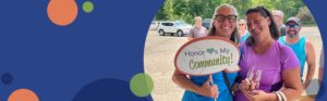 two teachers standing next to each other with one holding a sign that reads Honor loves my community | Honor Credit Union