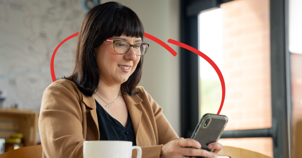 women on her phone having coffee | Honor Credit Union