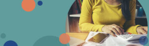 woman wearing a yellow shirt typing on a calculator at a desk | Honor Credit Union