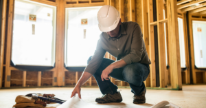 Contractor crouching looking at plans in a build site | Honor Credit Union