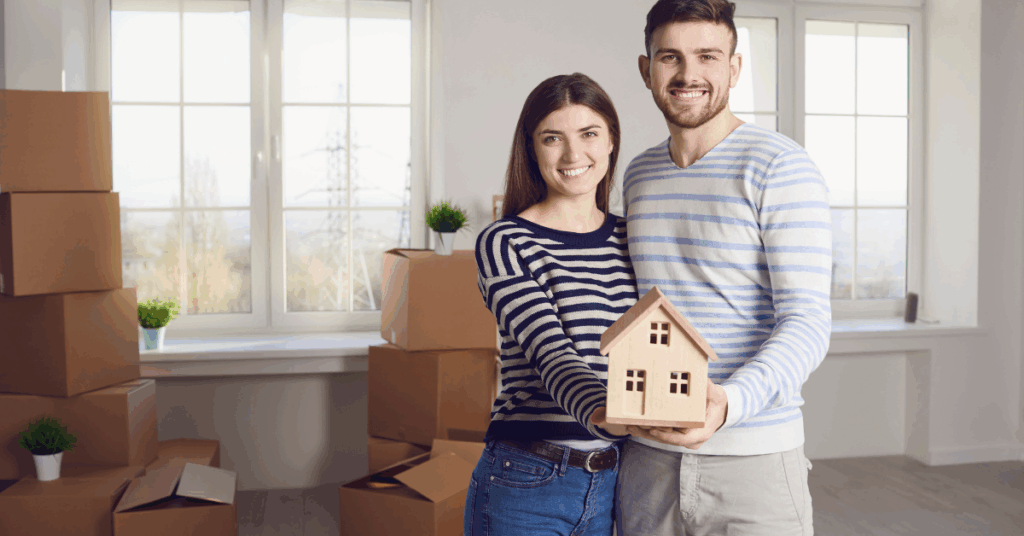 a young couple holding a small model of a house