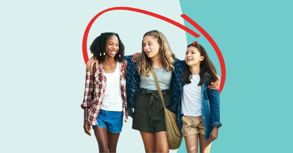 three pre-teen girls walking with their arms around eat other, while talking and smiling