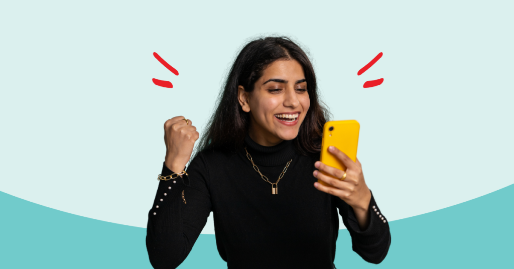 women holding a phone with one hand and making a fist with the other excited about maximizing her savings