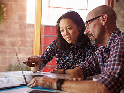 woman pointing at computer screen while man watches