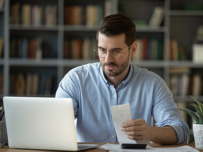 business owner holding a check looking at a computer screen