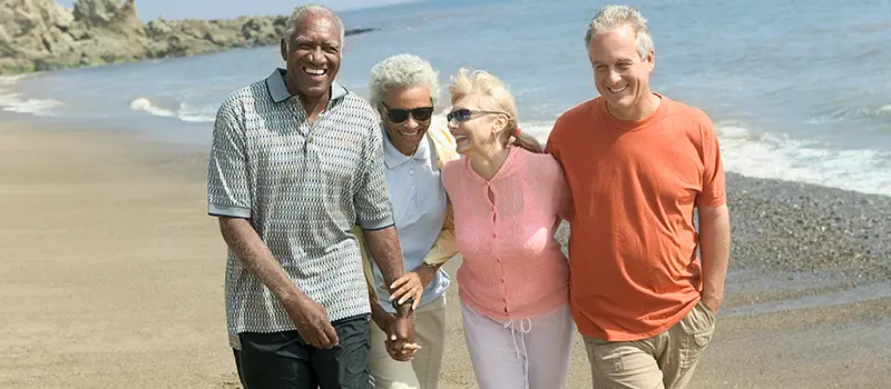 two older couples having fun walking along a beach
