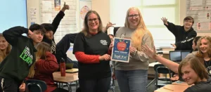 Teachers holding Honor Credit Union teacher award certificate surrounded by students | Honor Credit Union