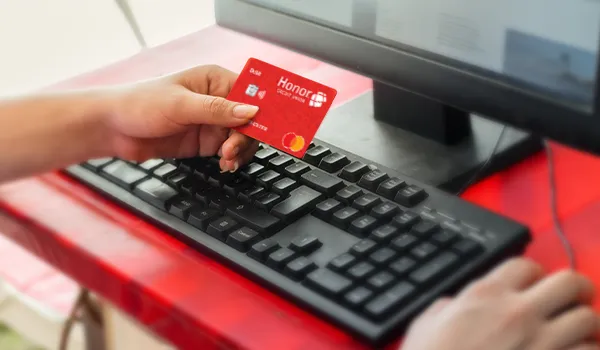 person holding an honor debit card next to a computer