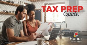 man and woman looking at paperwork at a table with text on image promoting honor's tax prep guide | Honor Credit Union