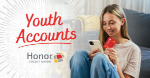 photo of a teenager looking at a phone while holding an honor debit card | Honor Credit Union