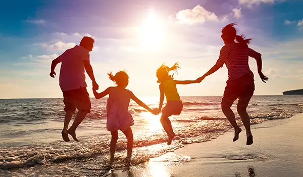 family jumping near the water at a beach