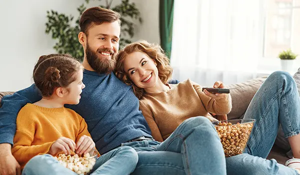 man and woman sitting on a couch with their daughter