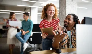 a group of co-workers talking around desks in a building office setting | Honor Credit Union