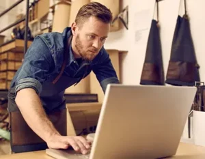 business owner looking at a laptop in his workshop | Honor Credit Union