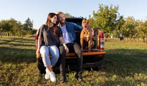 man and woman sitting on back of a truck with a dog | Honor Credit Union