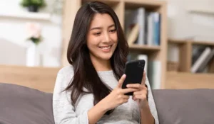 woman sitting on a couch looking at a mobile phone | Honor Credit Union
