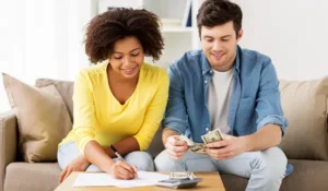 man and woman sitting on a couch counting money | Honor Credit Union