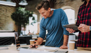 man on his laptop with coffee and another man next to him with an ipad | Honor Credit Union