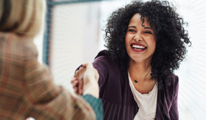 women smiling and shaking hands | Honor Credit Union